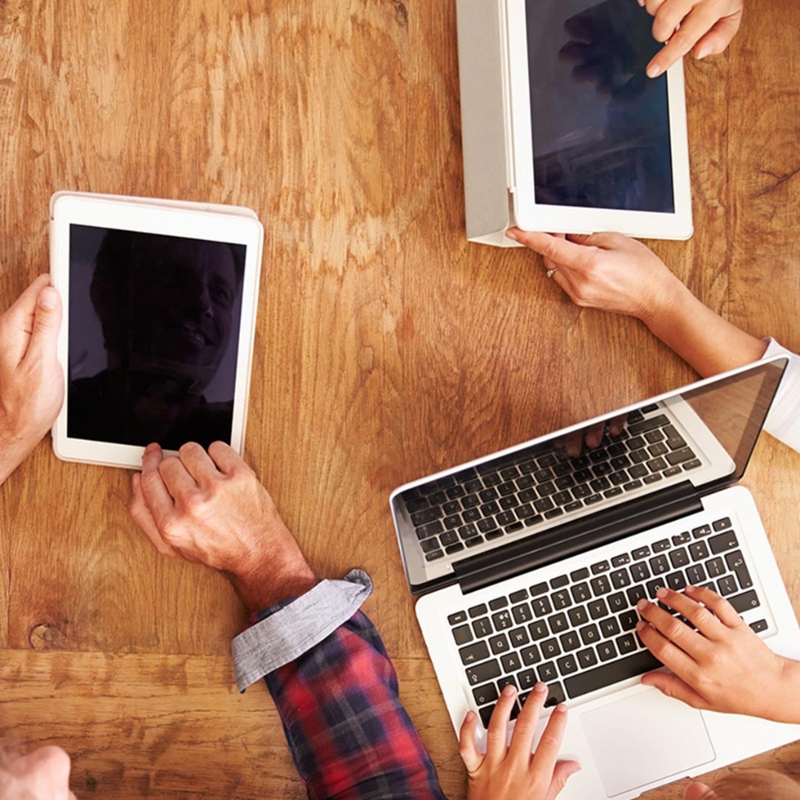 People sitting on table and working on laptop and tablet