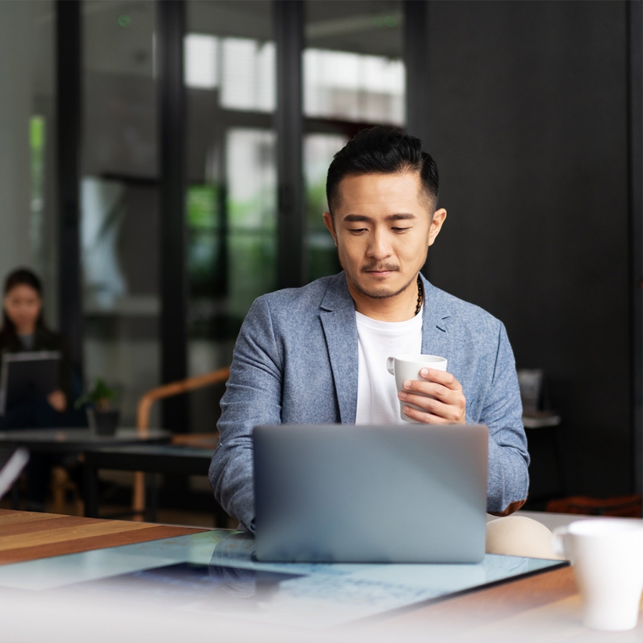 man with cup of tea working on laptop